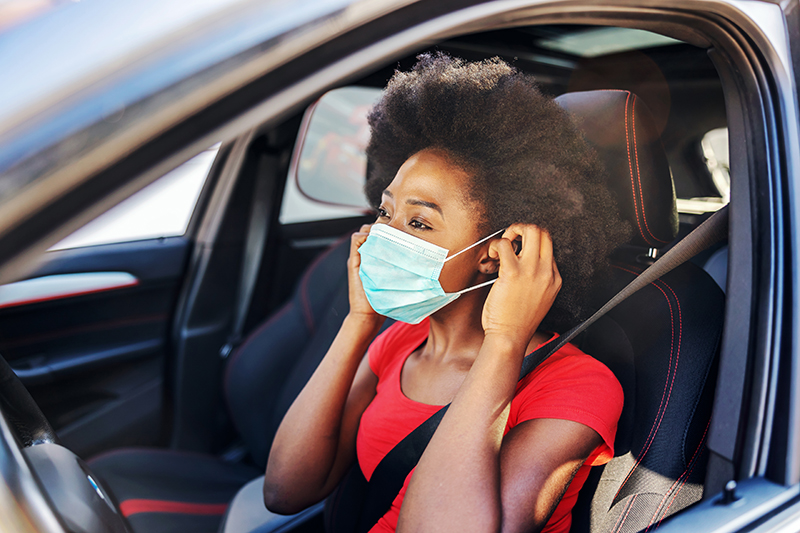 Young woman putting a mask on before she drives